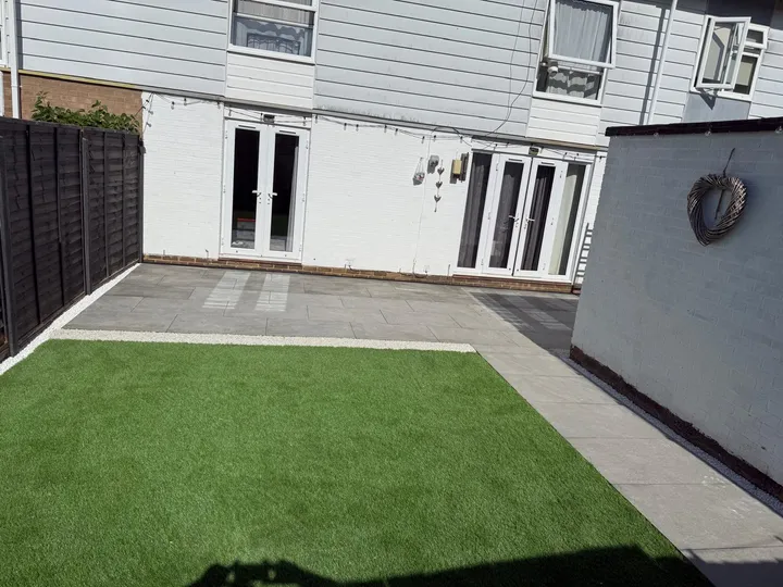 Artificial lawn beside a grey porcelain patio strip at the rear of a white rendered extension
