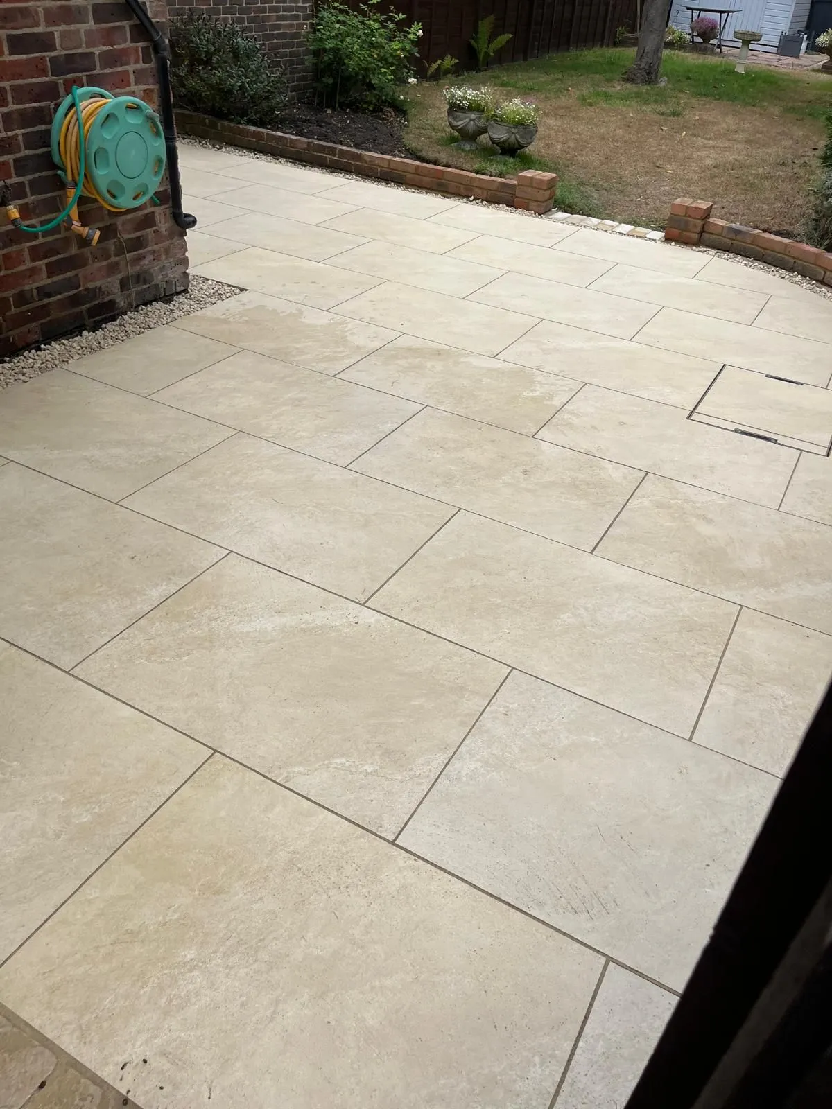 Cream porcelain paved patio with brick retaining wall