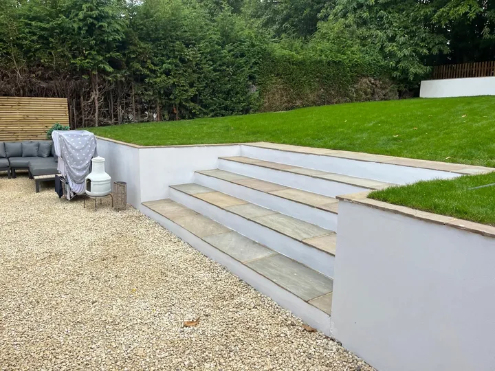 Sandstone steps rising from gravel courtyard up to a perfectly laid new lawn