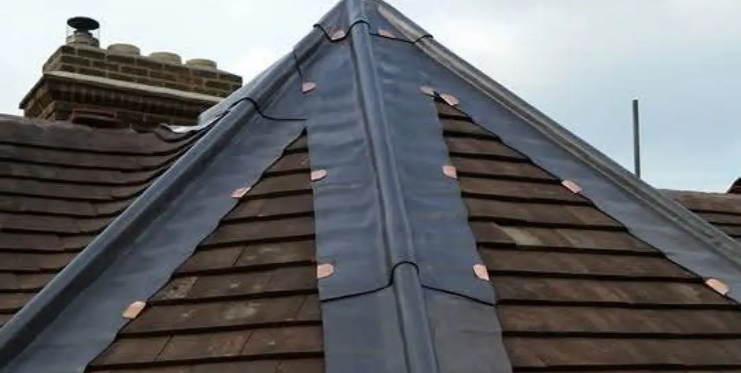 Pristine lead-clad hip with copper tacks meeting clay tile