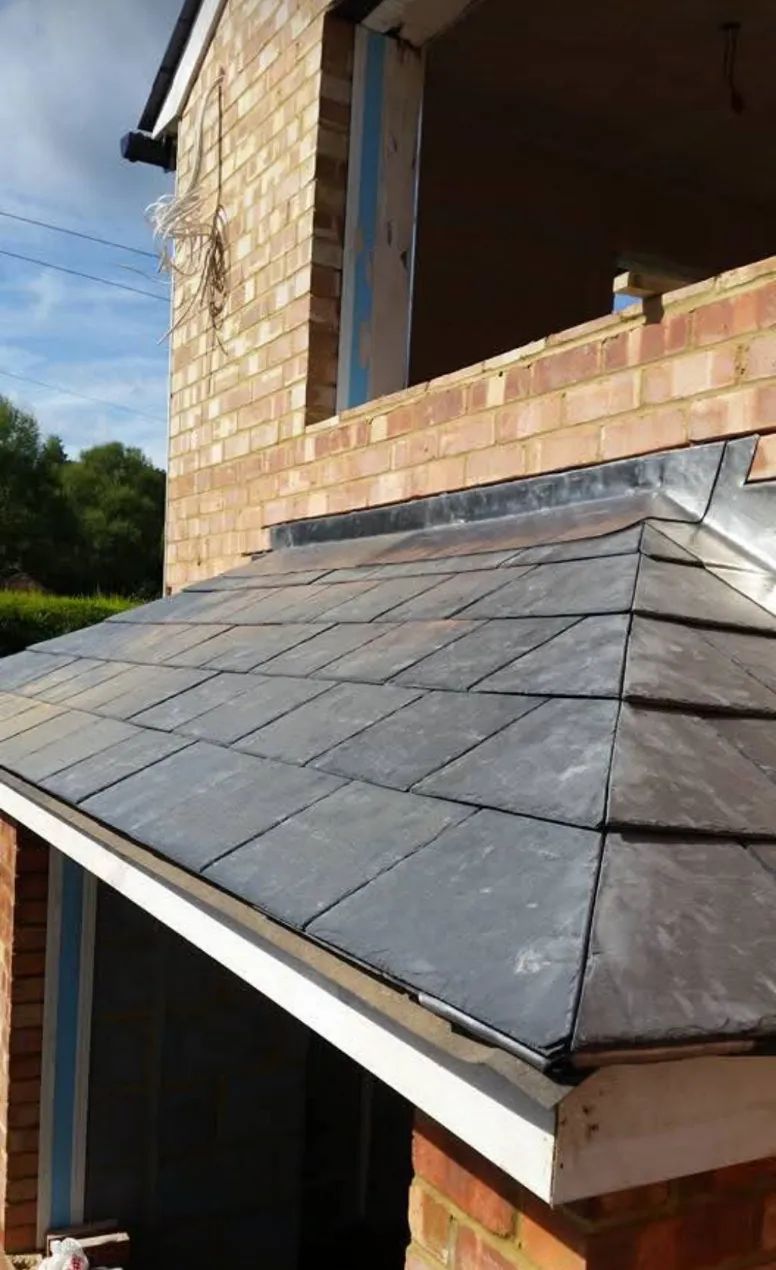 Finished slate hip roof with leadwork flashing over porch
